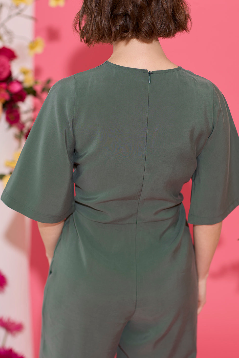 Wide leg, short sleeve petite jumpsuit in green, worn by model, back view close up