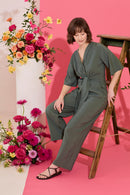 Wide leg, short sleeve petite jumpsuit in green, worn by model leaning