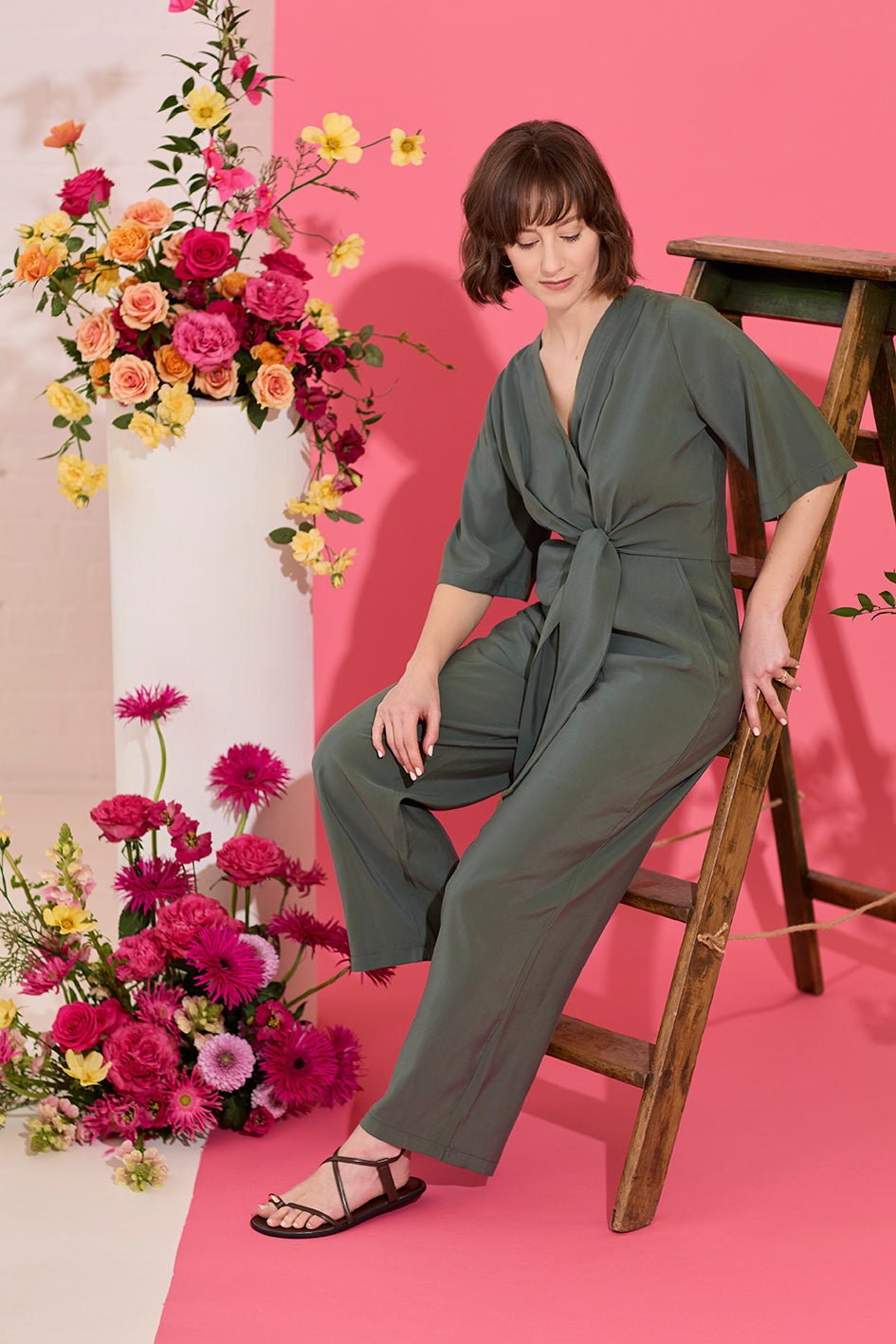 Wide leg, short sleeve petite jumpsuit in green, worn by model leaning