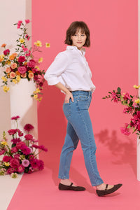 Slim, straight, high rise blue petite jeans worn by model walking, side view